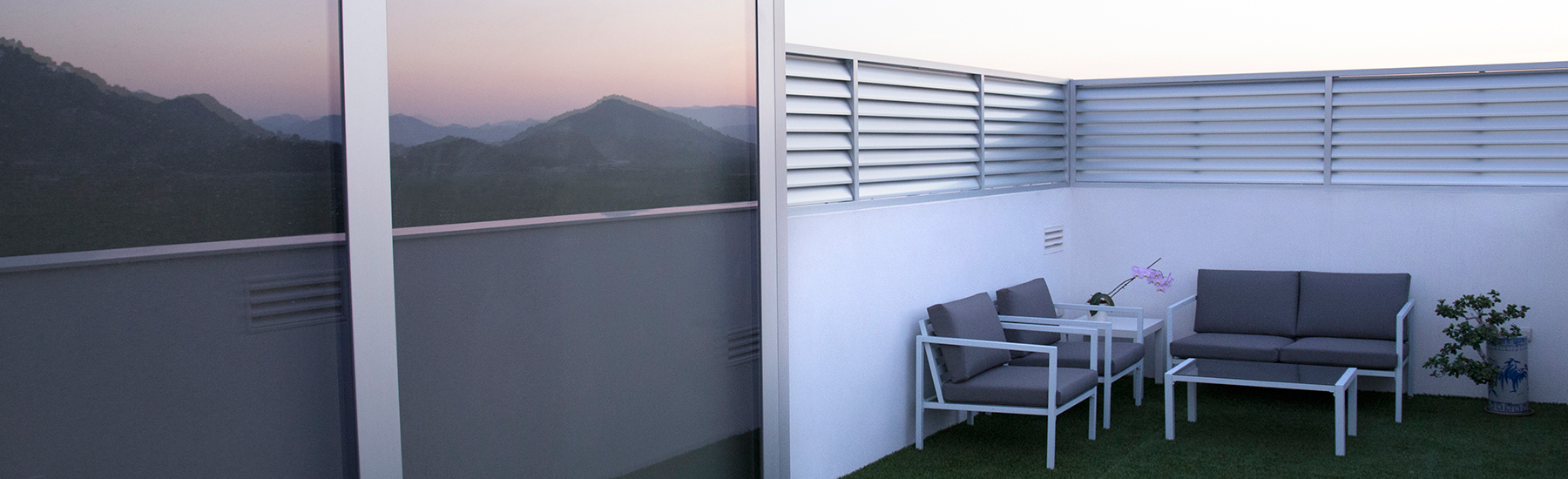 Finestral amb accés a terrassa al costat d'una gelosia fixa realitzats en alumini anonizado natural