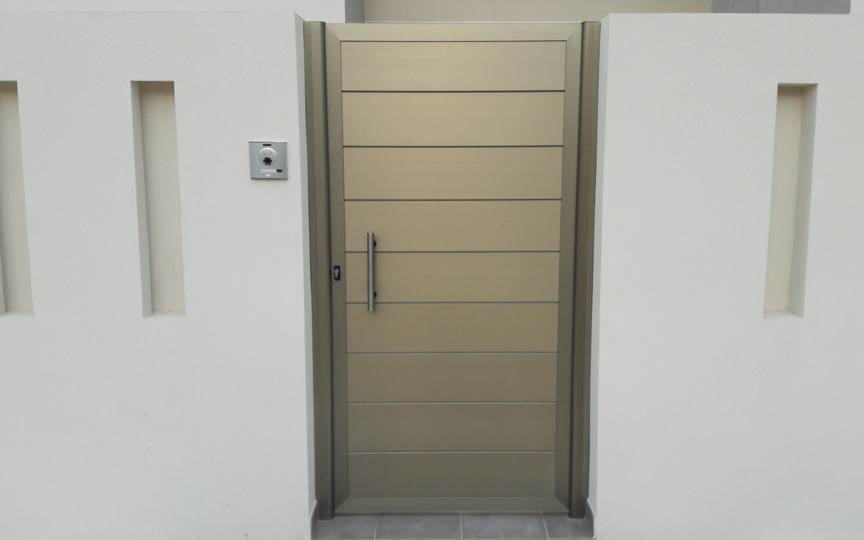 Porta d'accés a habitatge unifamiliar realitzada en alumini amb lames