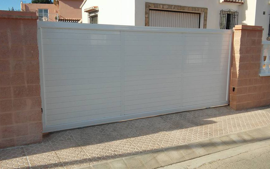 Porta corredissa realitzada en alumini blanc per a acces a un habitatge unifamiliar