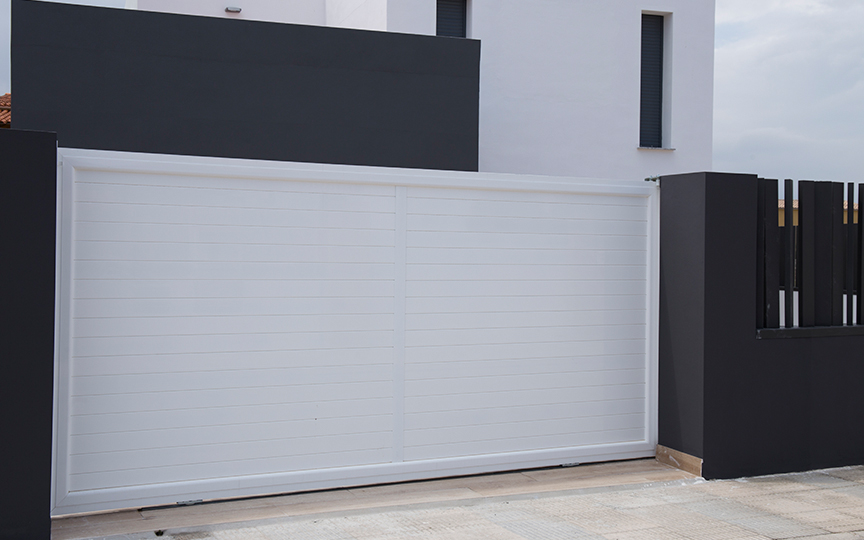 Porta corredissaa per a vivenda unifamiliar realitzada en alumini lacat en blanc
