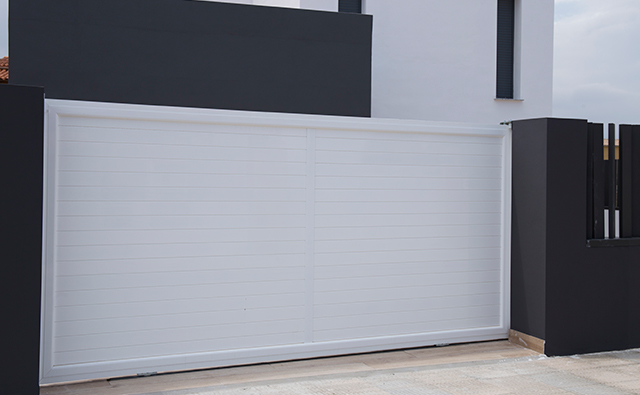Puerta corredera de aluminio lacado en blanco para acceso a garaje de una vivienda unifamiliar