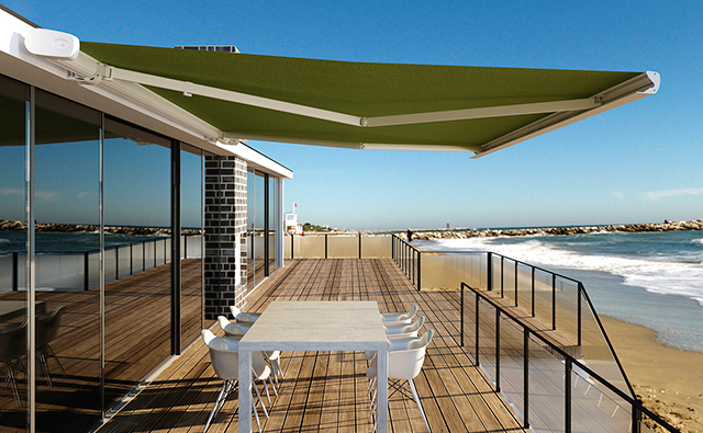 Terraza de playa con toldo automático de color verde y estructura en aluminio blanco