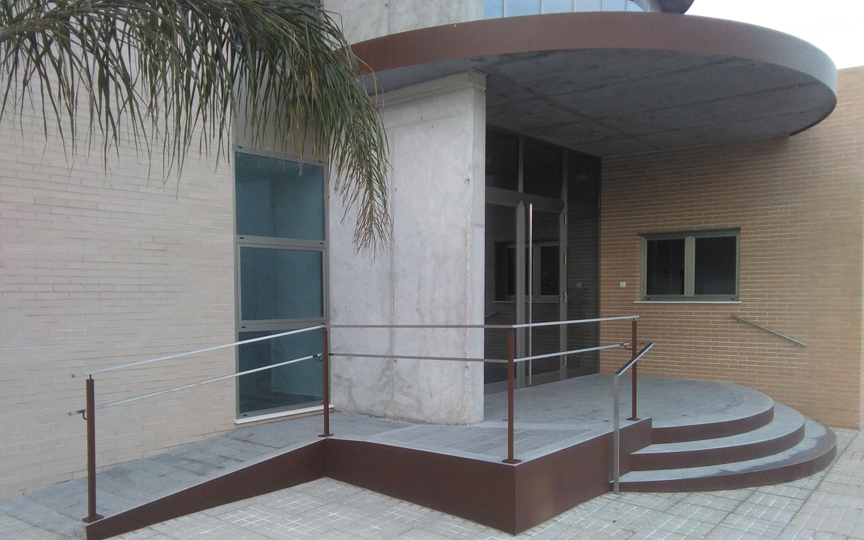 Entrada principal de la Casa de la Música amb portes d'alumini i barana de ferro oxidat amb pasamà inoxidable