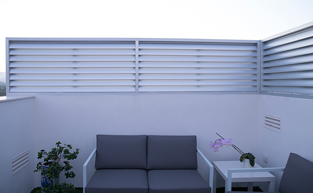 Celosía divisoria con lamas curvas de aluminio anodizado en la terraza de una vivienda ático