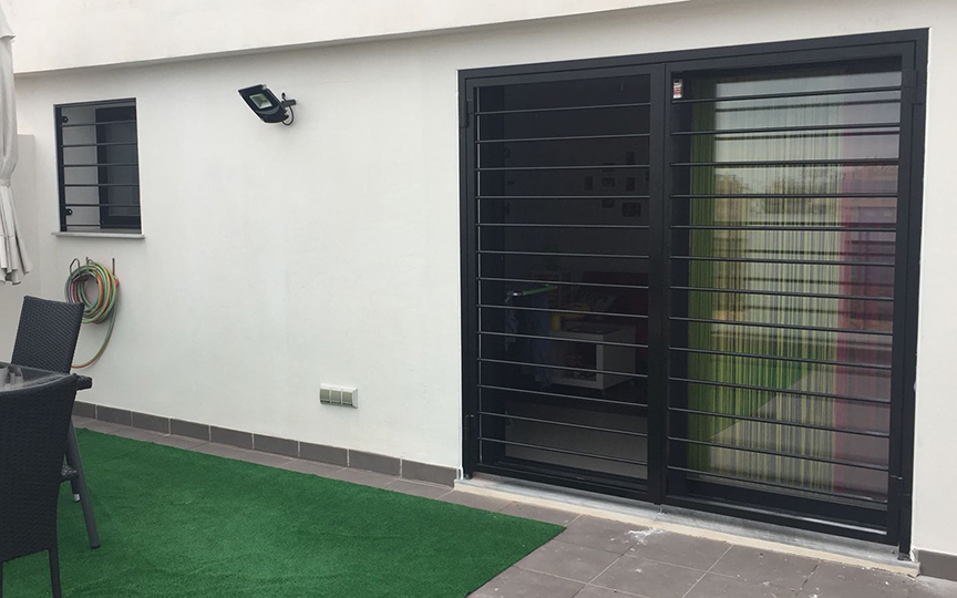 Ventana y ventanal de aluminio junto a rejas de hierro para acceso a terraza acabadas en color negro